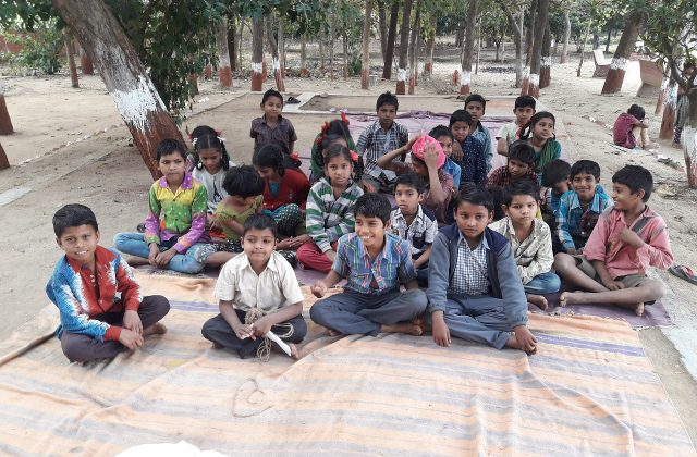 Adivasi children seated and studying in a classroom at a tribal academy in Gujarat